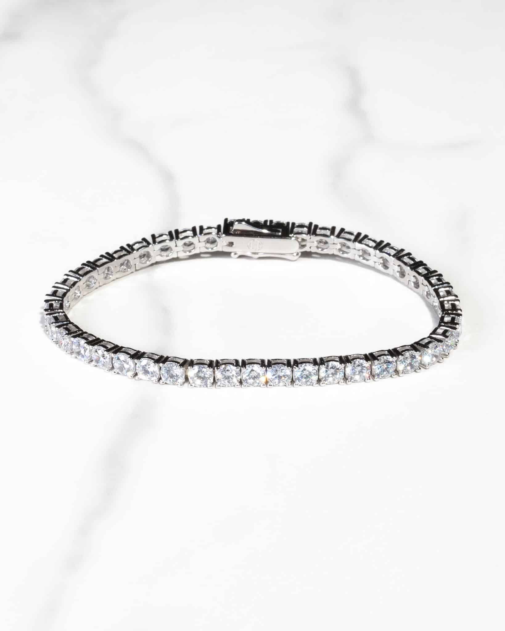 Ett tennisarmband i silver, 4 mm, med en rad gnistrande rundskurna diamanter, på en vit marmoryta.